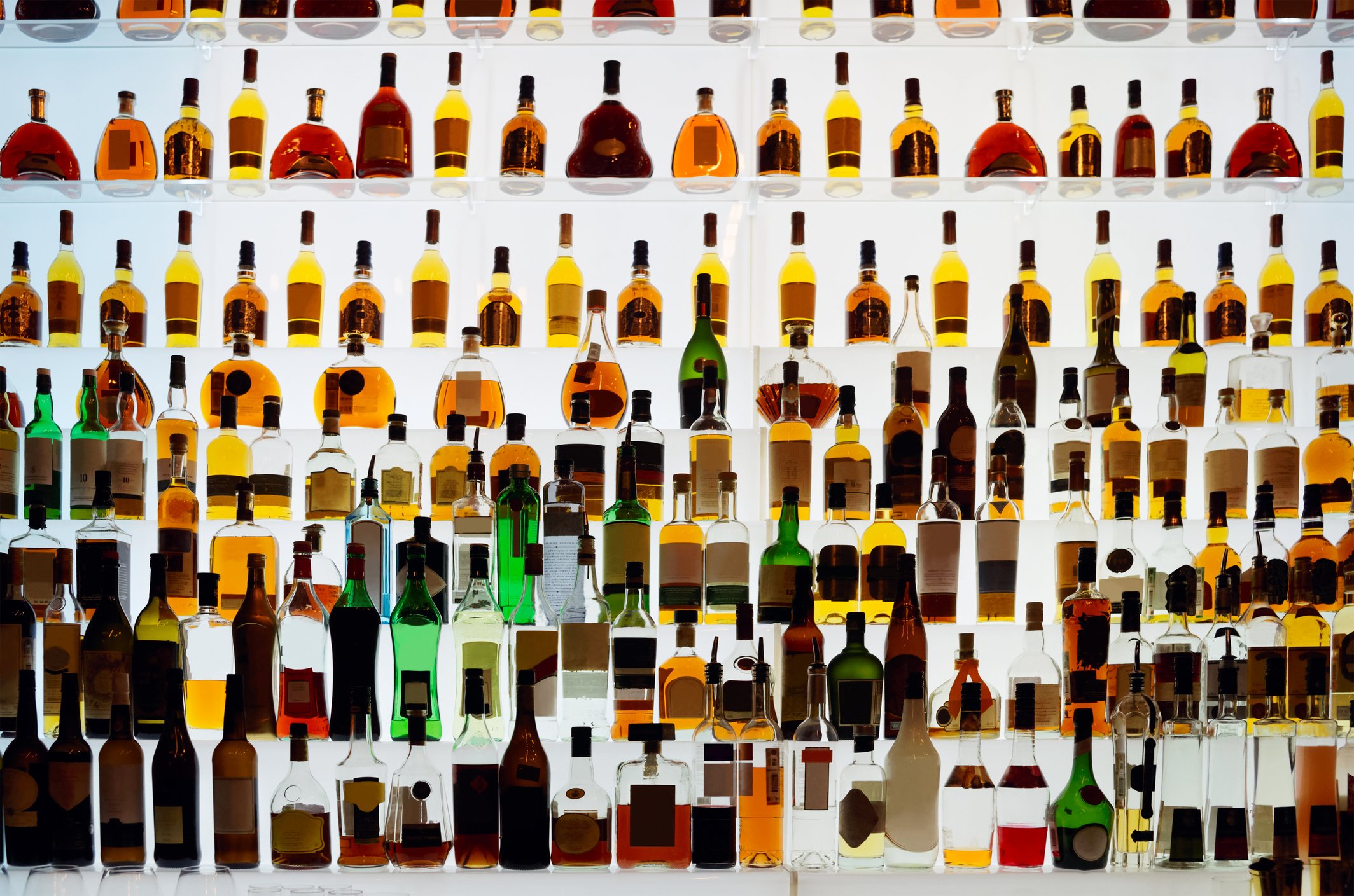 A large shelf of liquor bottles backlit with white lights.