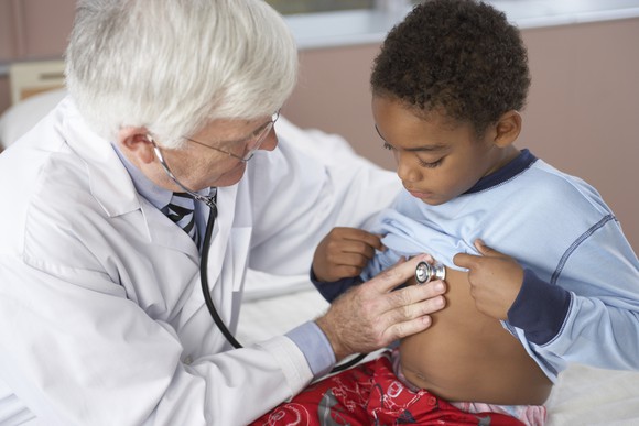Doctor listening to a boy's chest with a stethoscope 