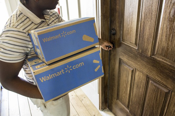 A man holding two Walmart boxes opening a door.