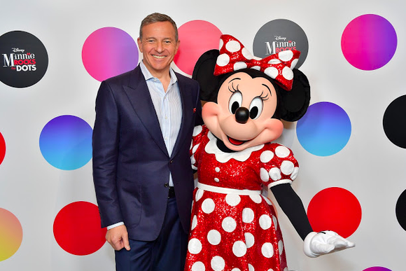 Disney CEO Bob Iger and Minnie Mouse pose in front of a polka-dotted backdrop.