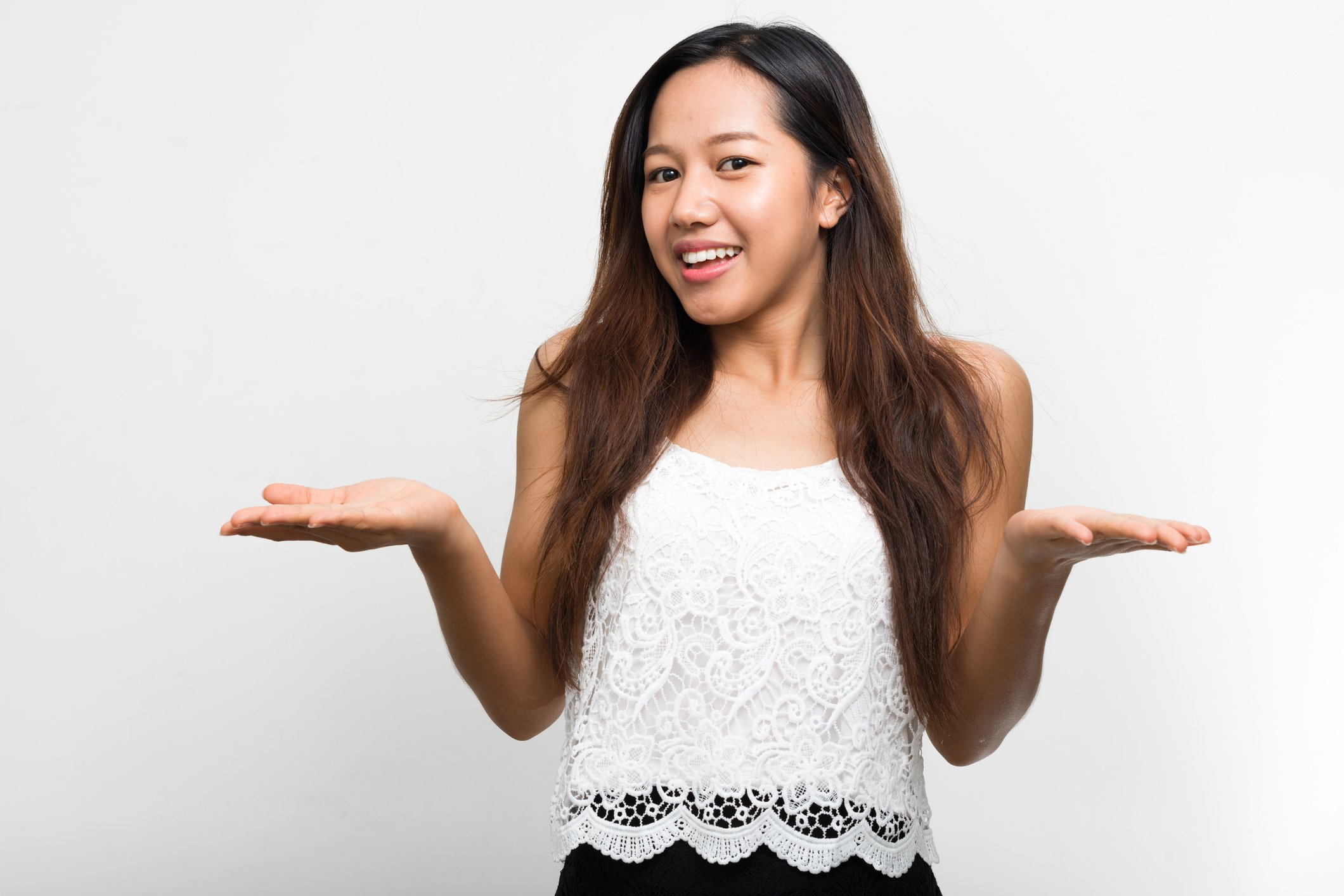 A millennial woman with long hair smiling and shrugging her arms and shoulders. 