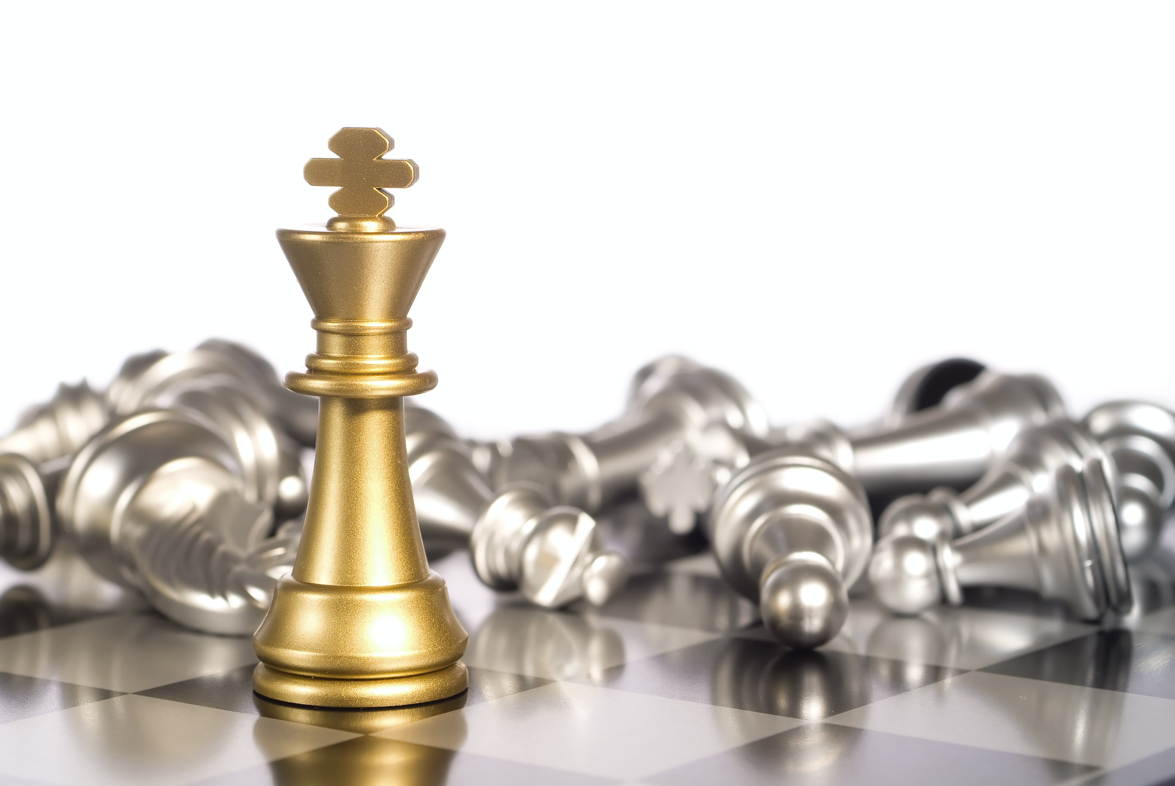 On a chess board, a golden king stands before toppled silver pieces.