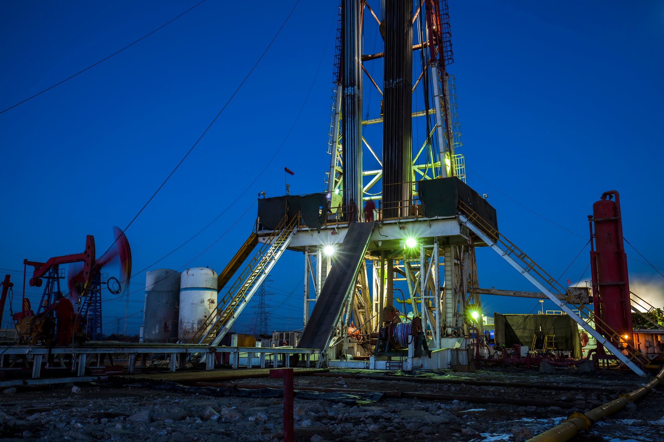 An oil drilling rigs with pump jacks in the background.