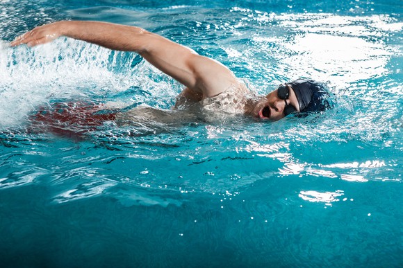 A person in a swimming cap and goggles swimming through the water.