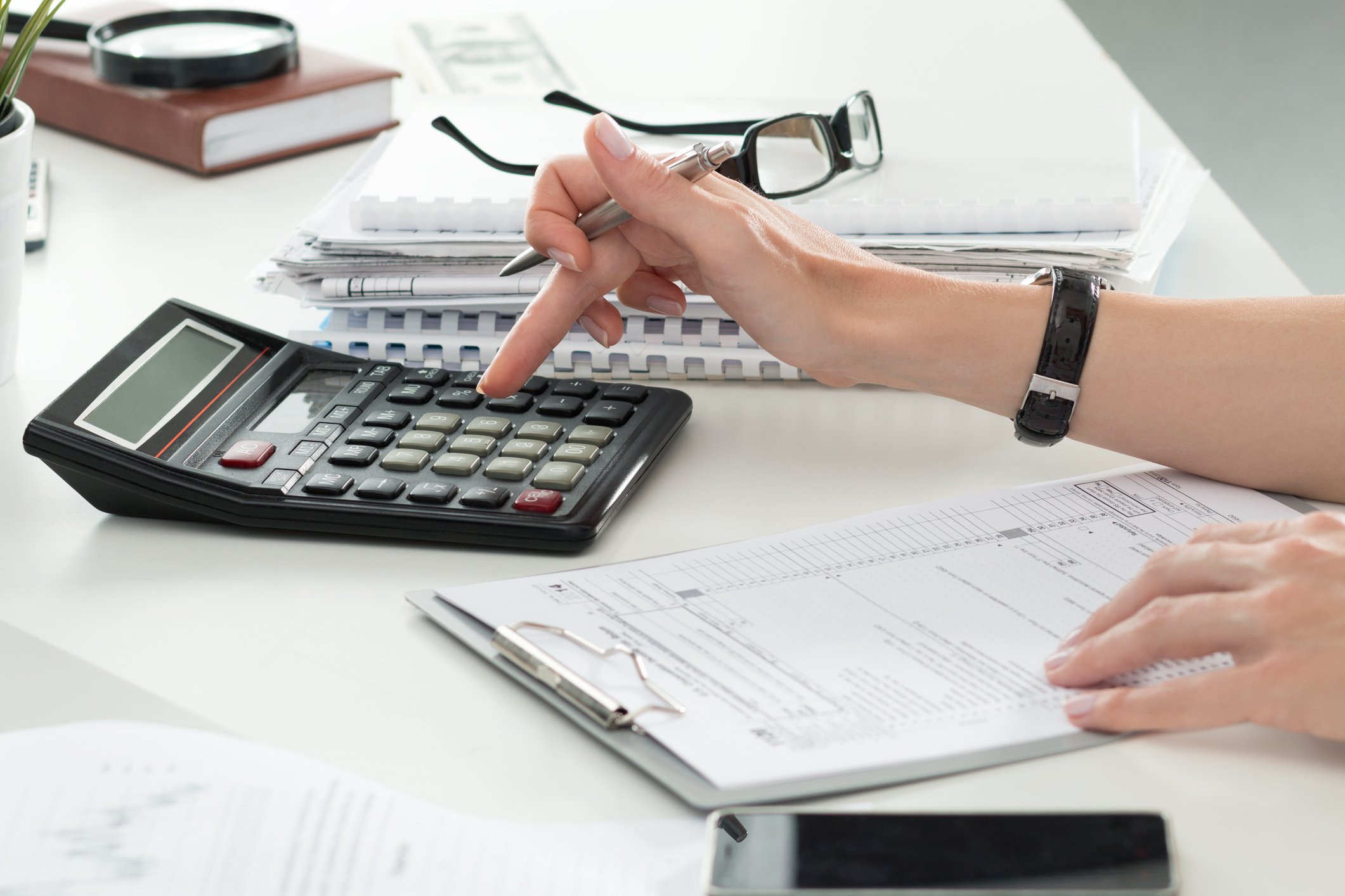 Woman using calculator with forms on a clipboard in front of her