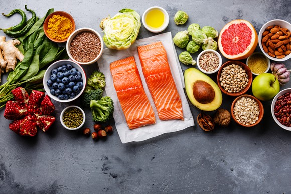 A spread of healthy foods including salmon, avacado, blueberries.