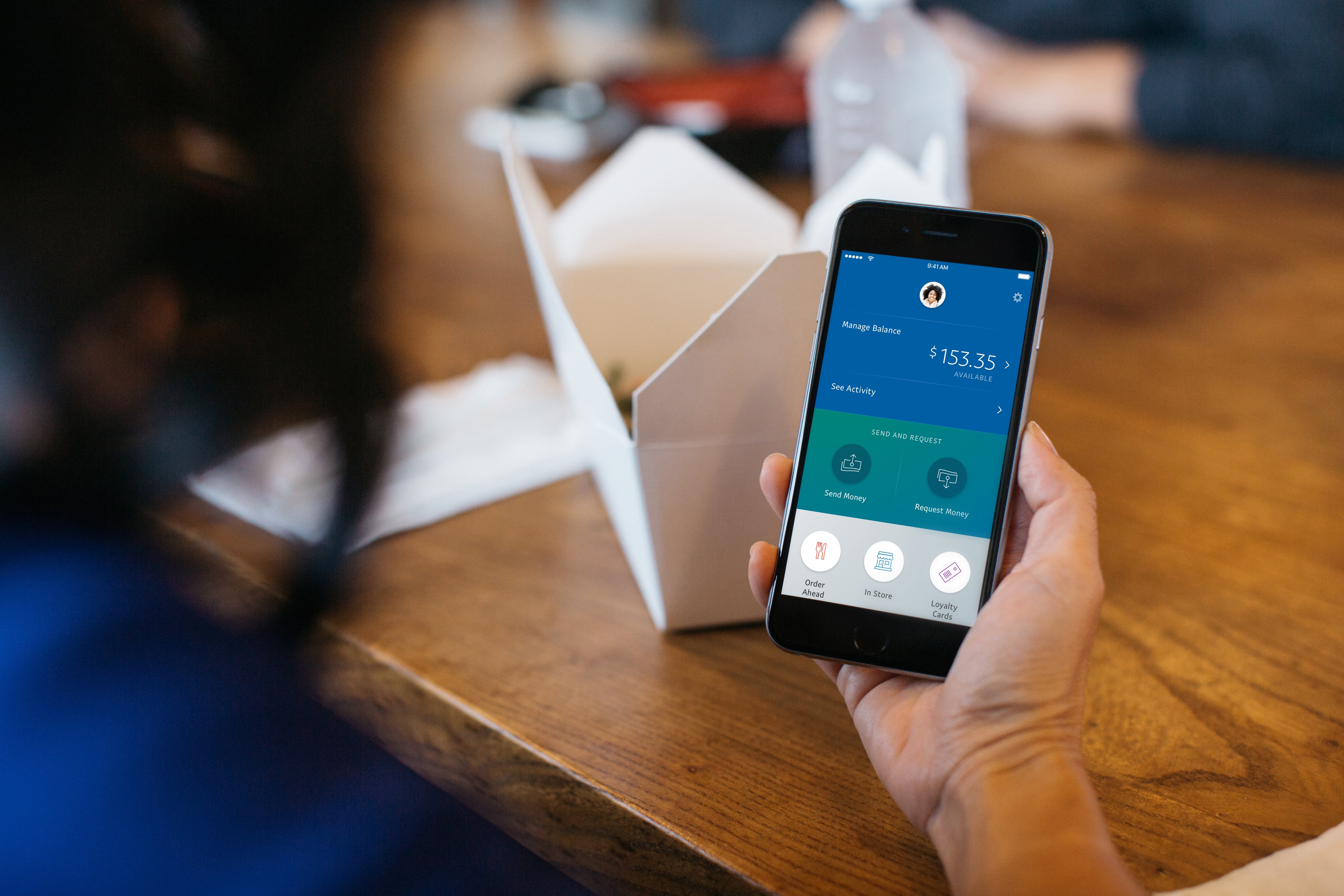 Person holding a smartphone showing PayPal app page.