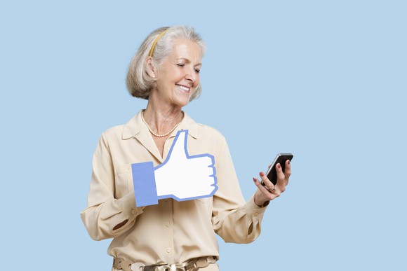 Mature woman giving a thumbs up on smart phone.