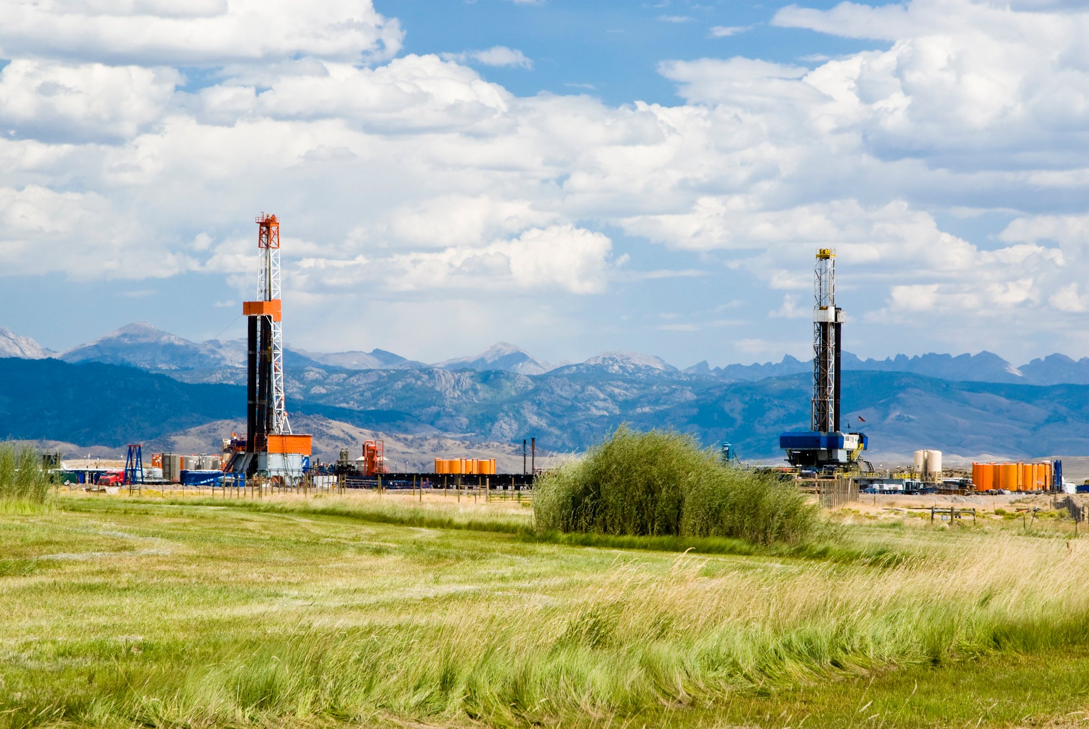 Drilling rigs against a backdrop of mountains