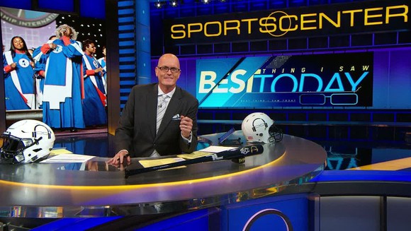 Sportscaster Scott Van Pelt sitting at a desk with ESPN Sports Center sign behind him