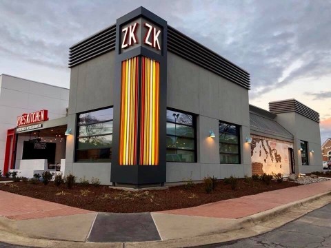 An external view of Zoe's new pilot store in North Carolina. The building is ultra-modern in gray and black, and features a vertical bank of yellow and orange lights on the corner capped with a ZK logo.