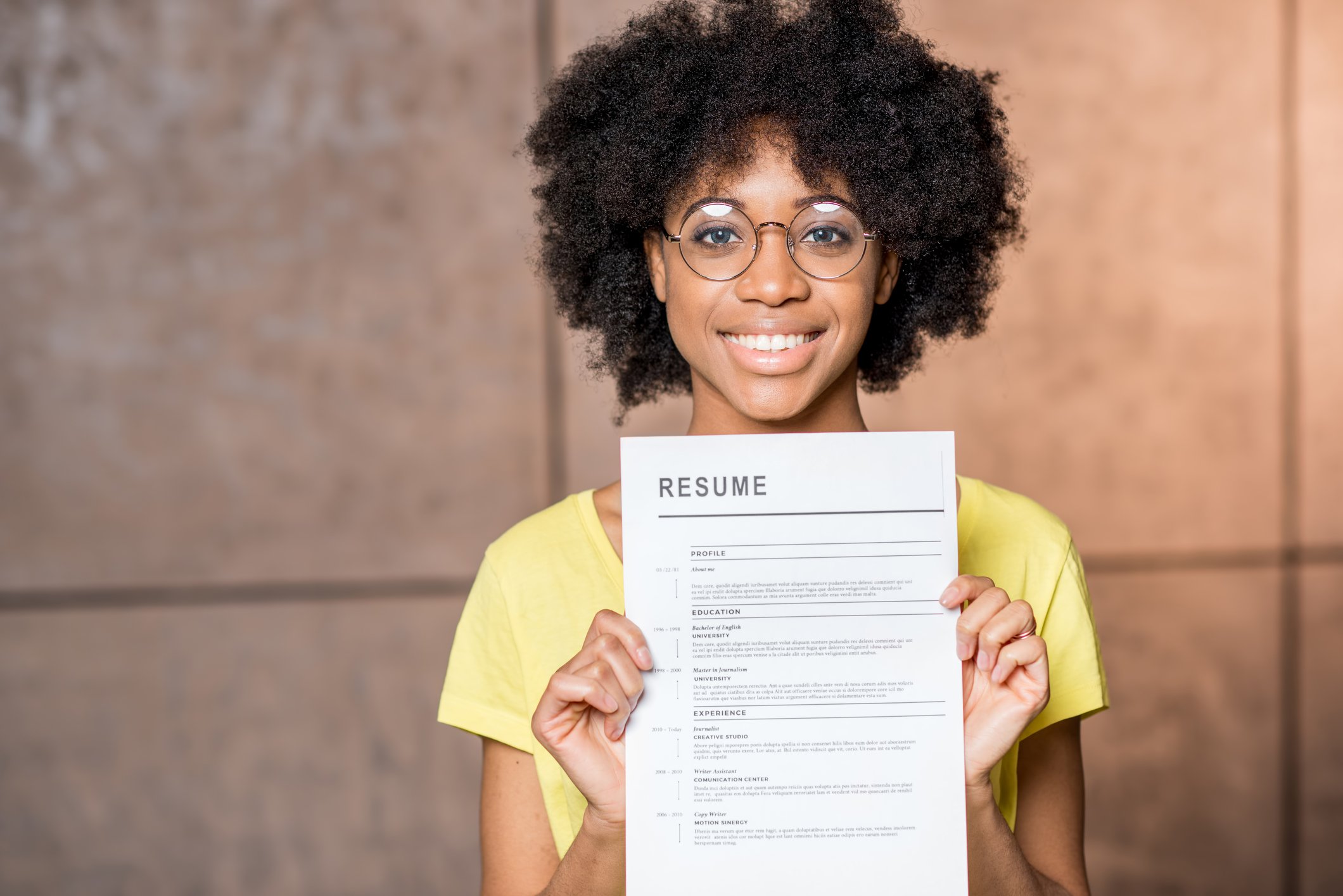 A young woman holds up her resume.