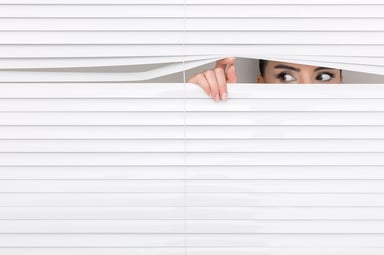 Woman peeking through window blinds