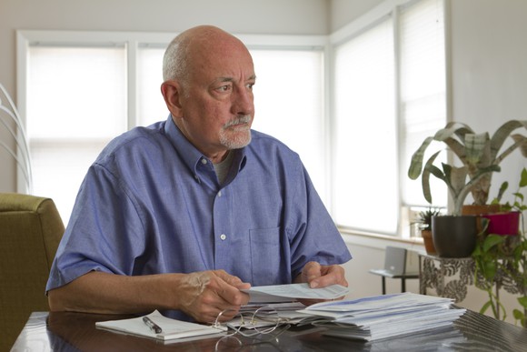 A worried elderly man examining his finances.