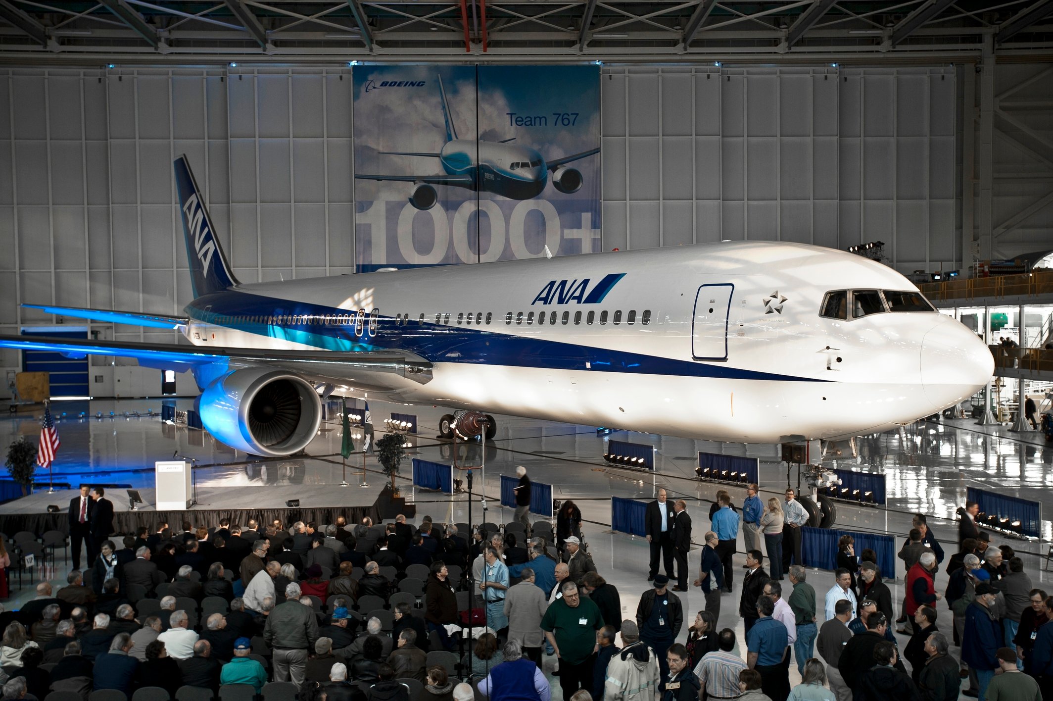 A Boeing 767 in a hanger surrounded by people.