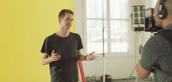 Snap Inc. CEO Evan Spiegel stands in front of a yellow backdrop and explains the new Snapchat redesign.