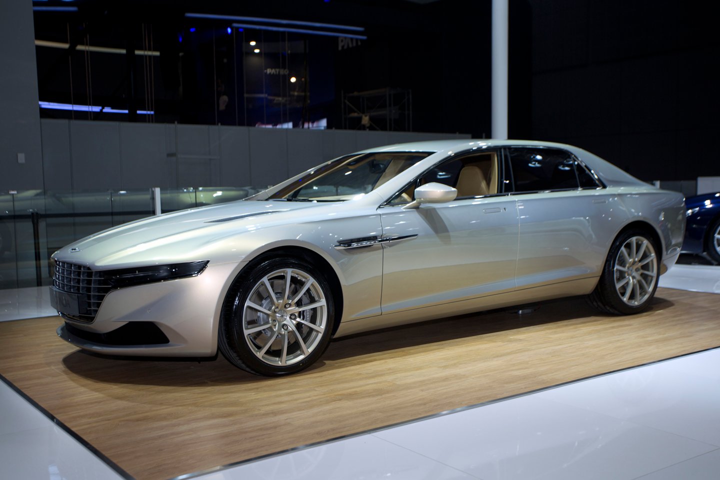 A 2015 Lagonda Taraf, a sleek luxury sedan, in silver on an auto-show display stand.
