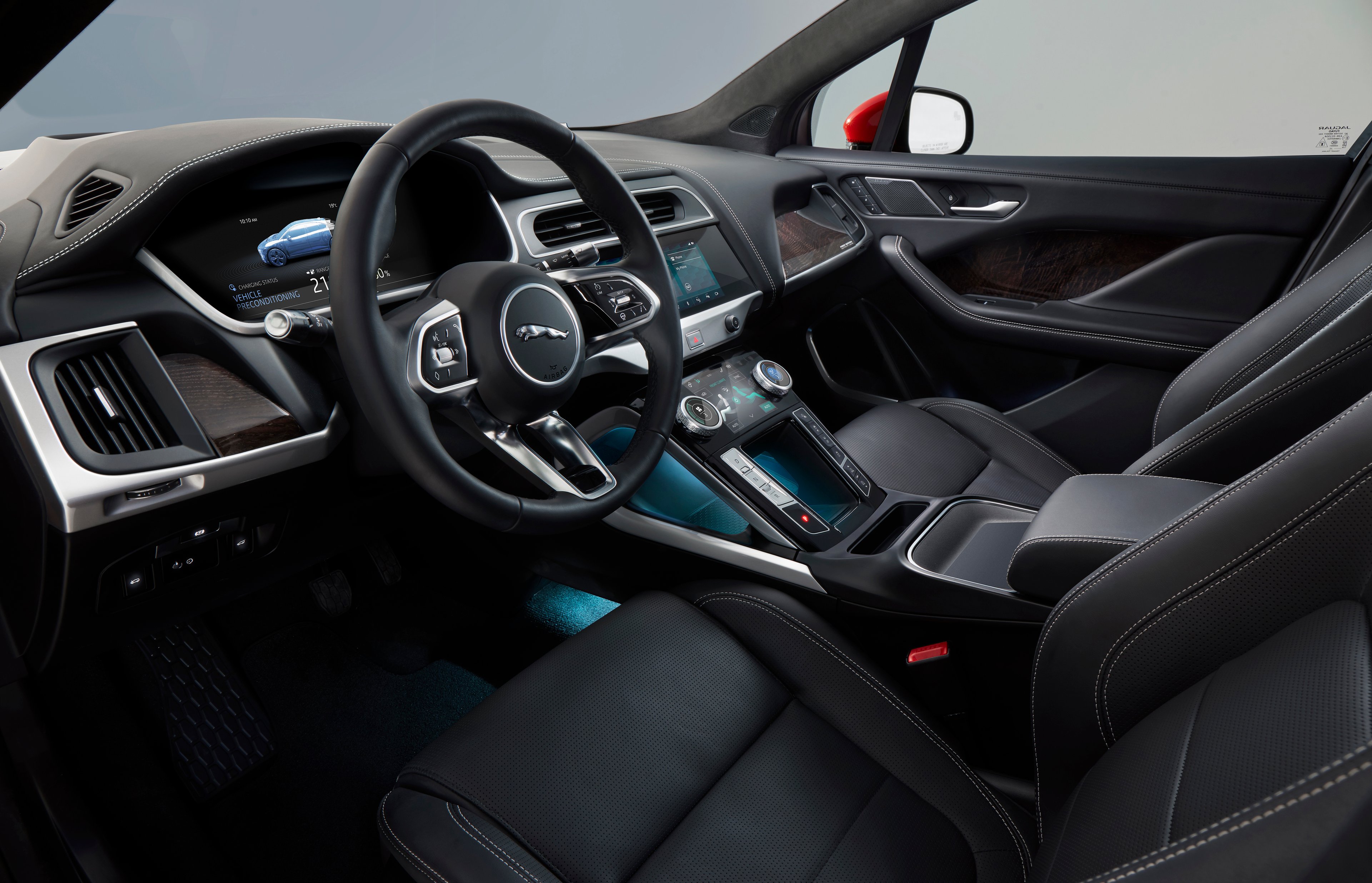 A view of an I-Pace's front seats and dashboard, showing black leather, dark wood, and brushed-metal trim.