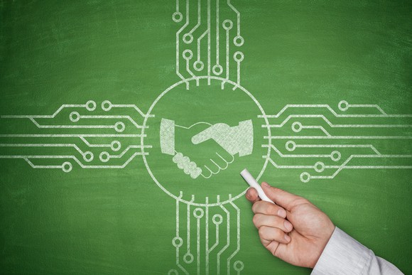 A chalkboard with circuits and two hands shaking drawn on it.