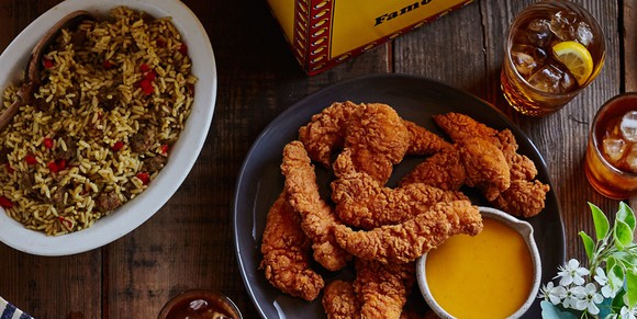 Platter of Bojangles' fried chicken tenders with dipping sauce, served with "dirty rice" and iced tea.