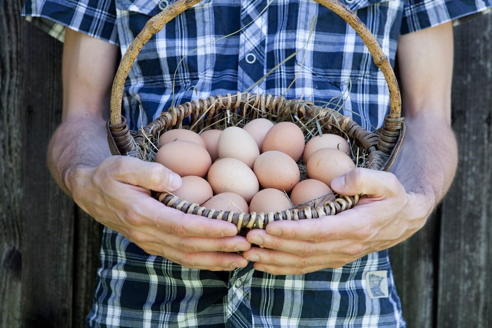 A man holding a basket of eggs. 