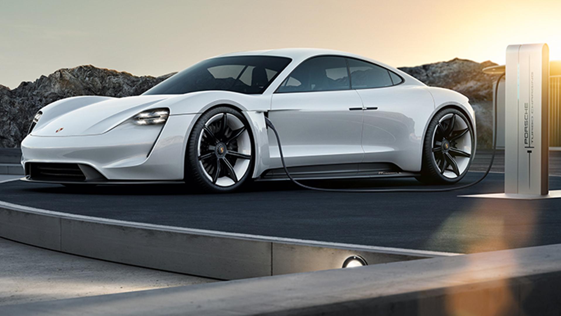The Porsche Mission E Concept, a white four-door car with a curved sports-car roofline, at a recharging station.