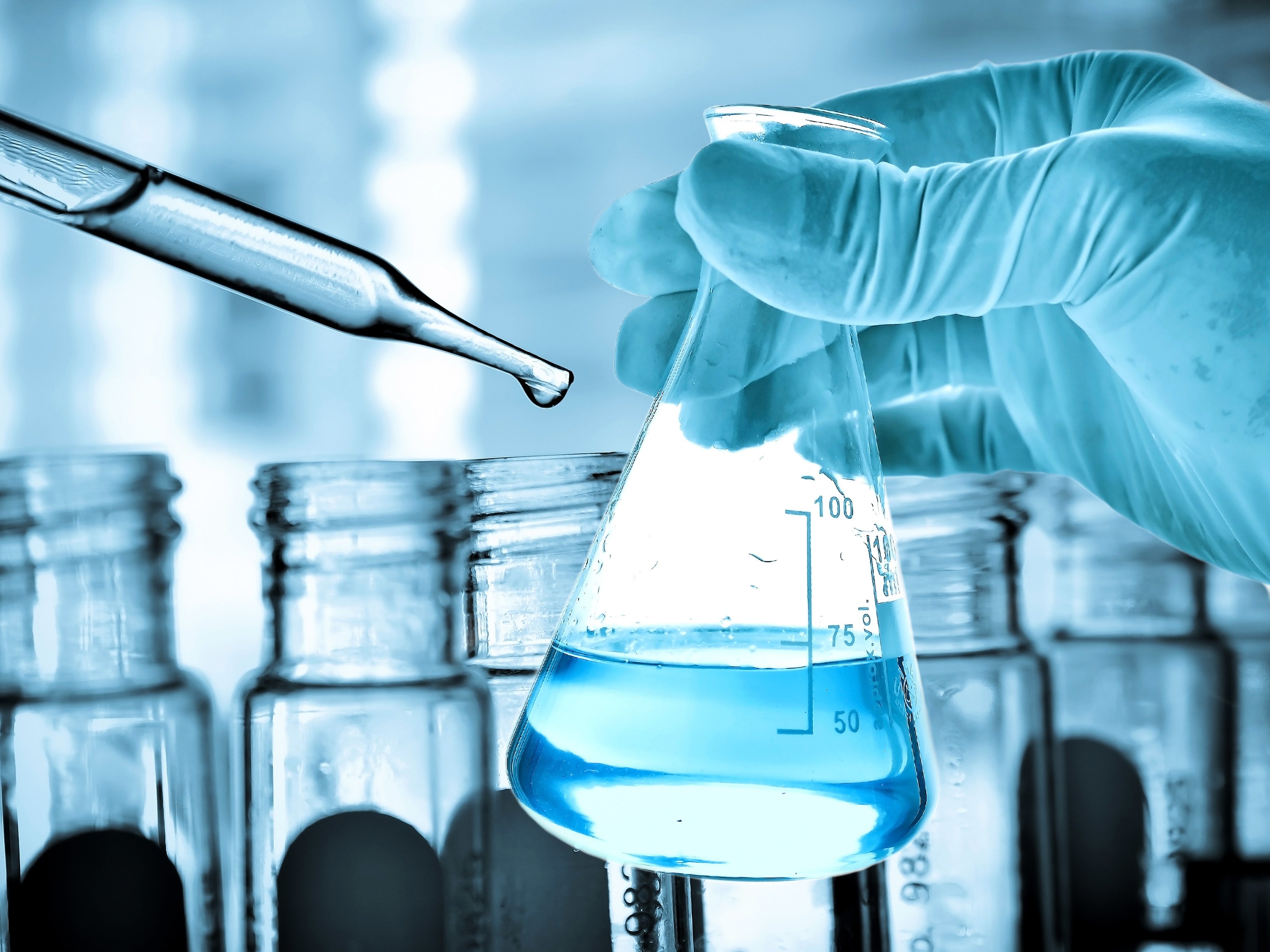 Gloved hand holding flask next to dropper