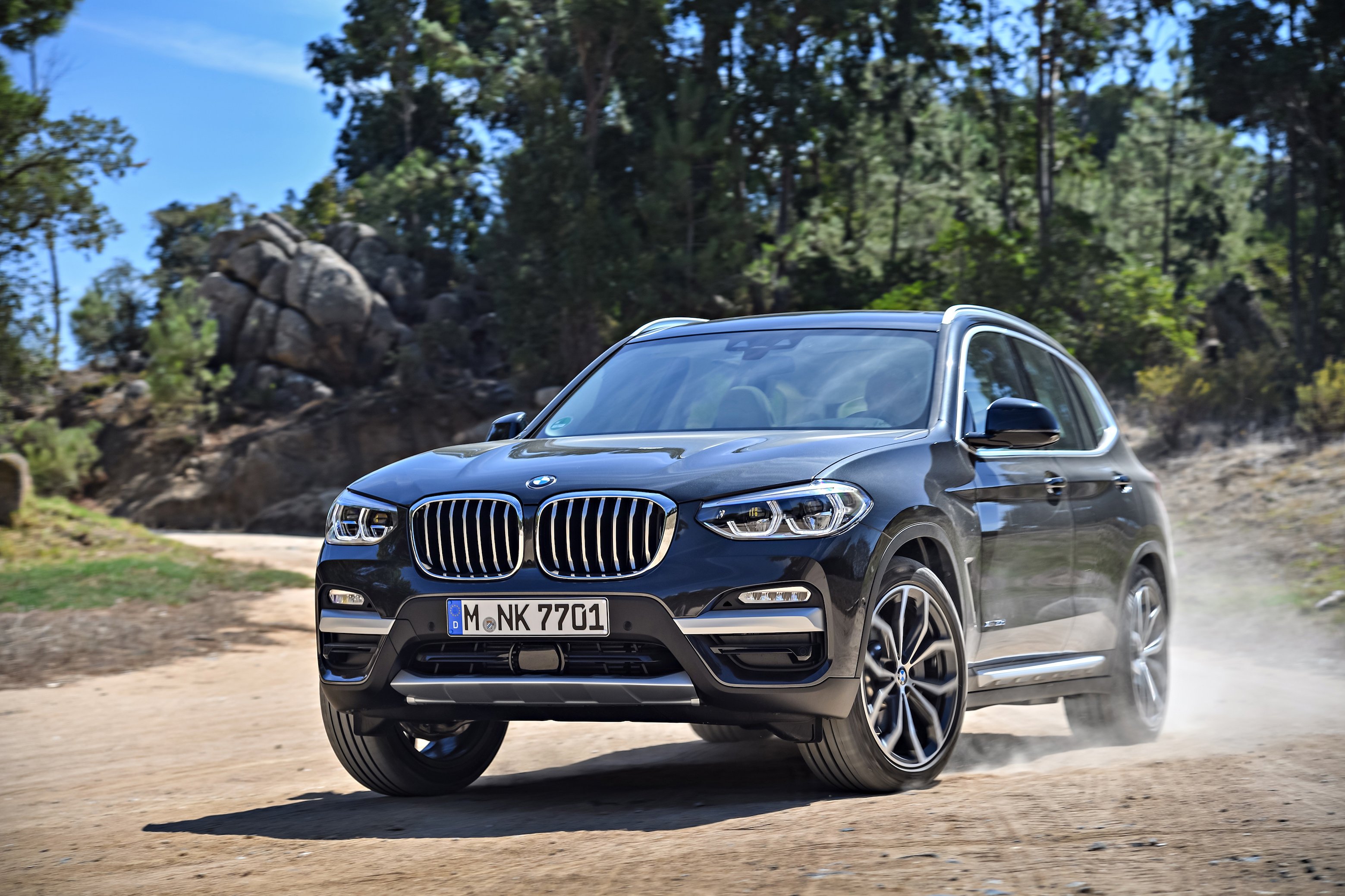 A 2018 BMW X3, a compact crossover SUV, on a dirt road.