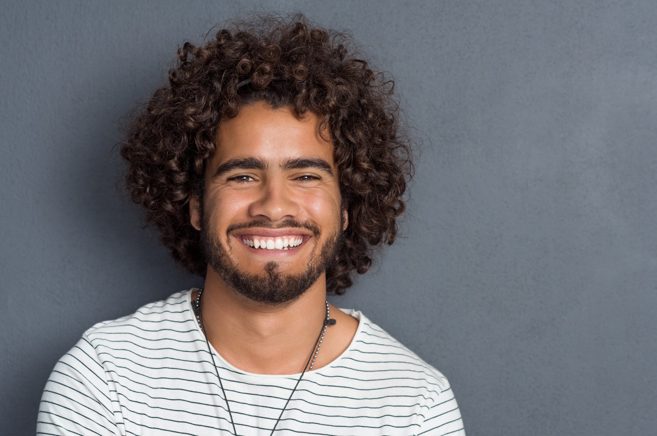 Smiling younger man against gray background.