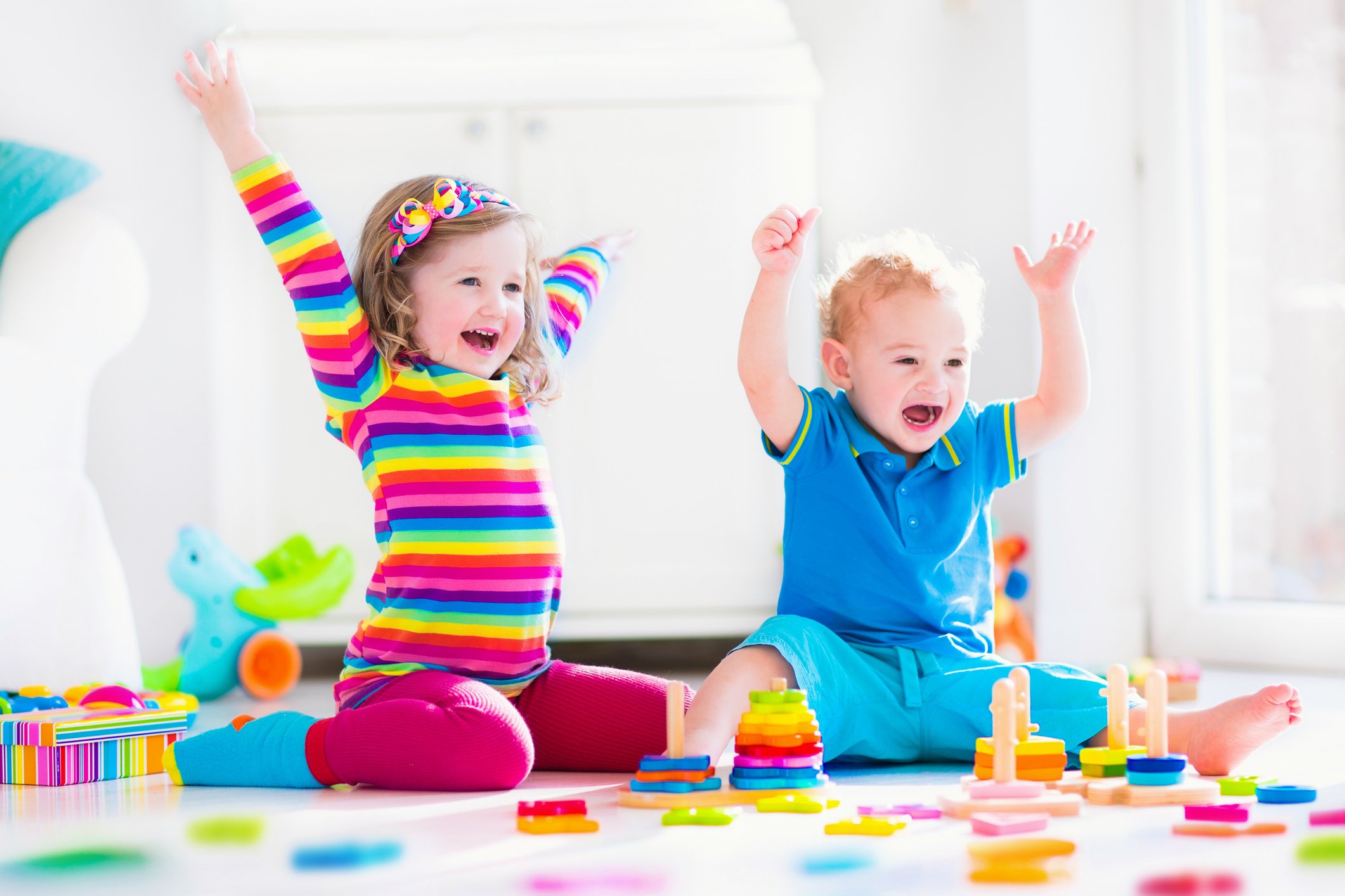 Two toddlers playing with toys and cheering