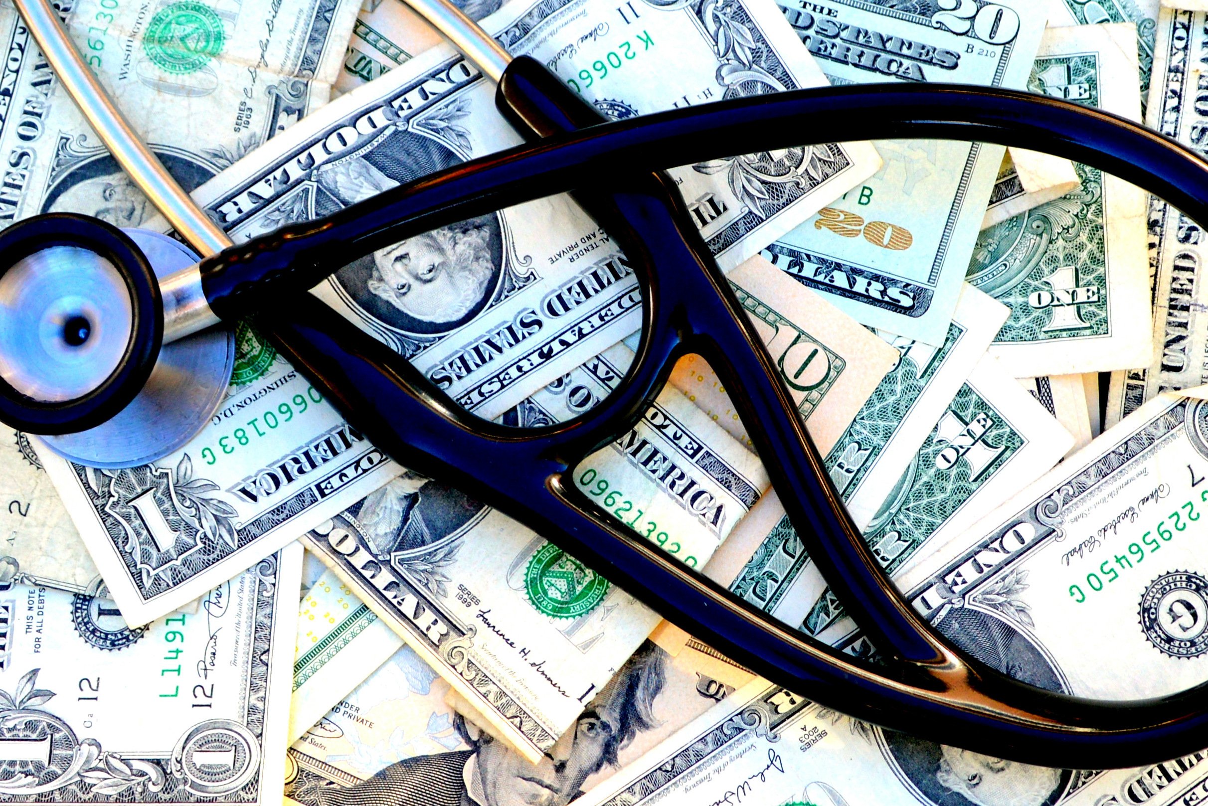 Dark blue stethoscope on top of dollar bills