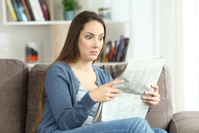 Confused woman reading a newspaper.