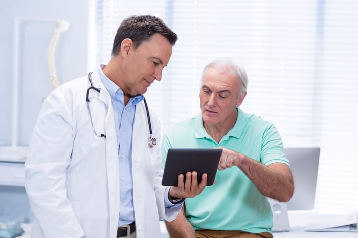 Doctor with patient reading a tablet.