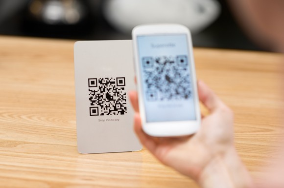 Shopper uses a merchant's displayed QR code to pay for a purchase.