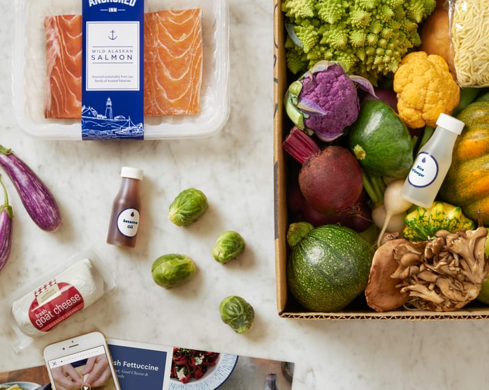 A sample box of ingredients from Blue Apron includes salmon, goat cheese, and different vegetables