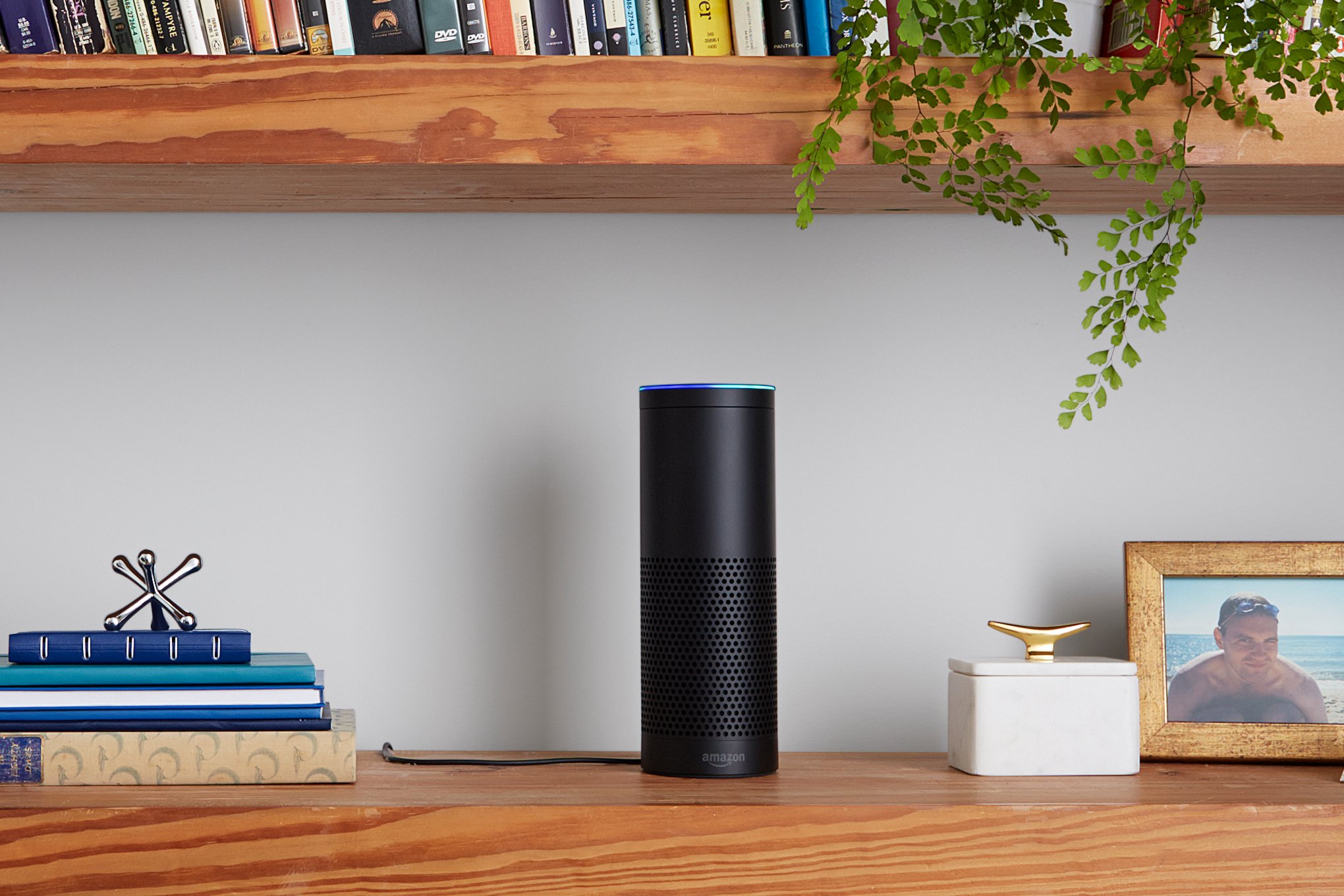 A black Amazon Echo smart speaker on a bookshelf.