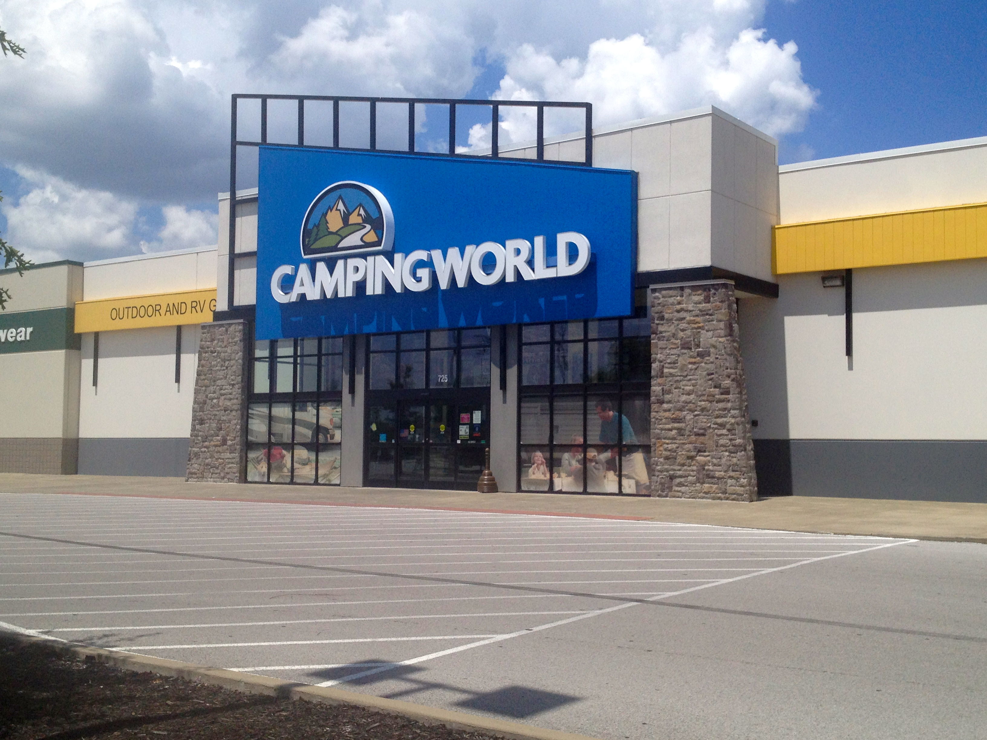 Camping World retail location from the outside, across an empty street in front of the entrance, on a partly cloudy day.