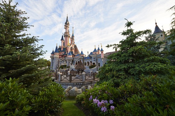 A glimpse through the trees at the Disney castle at Disneyland Paris.