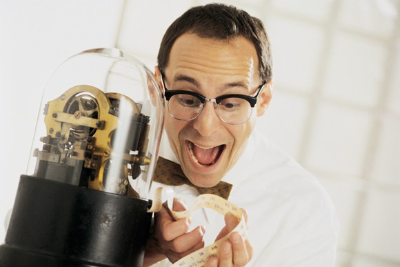 A stock investor excitedly reading a stock market ticker tape. 
