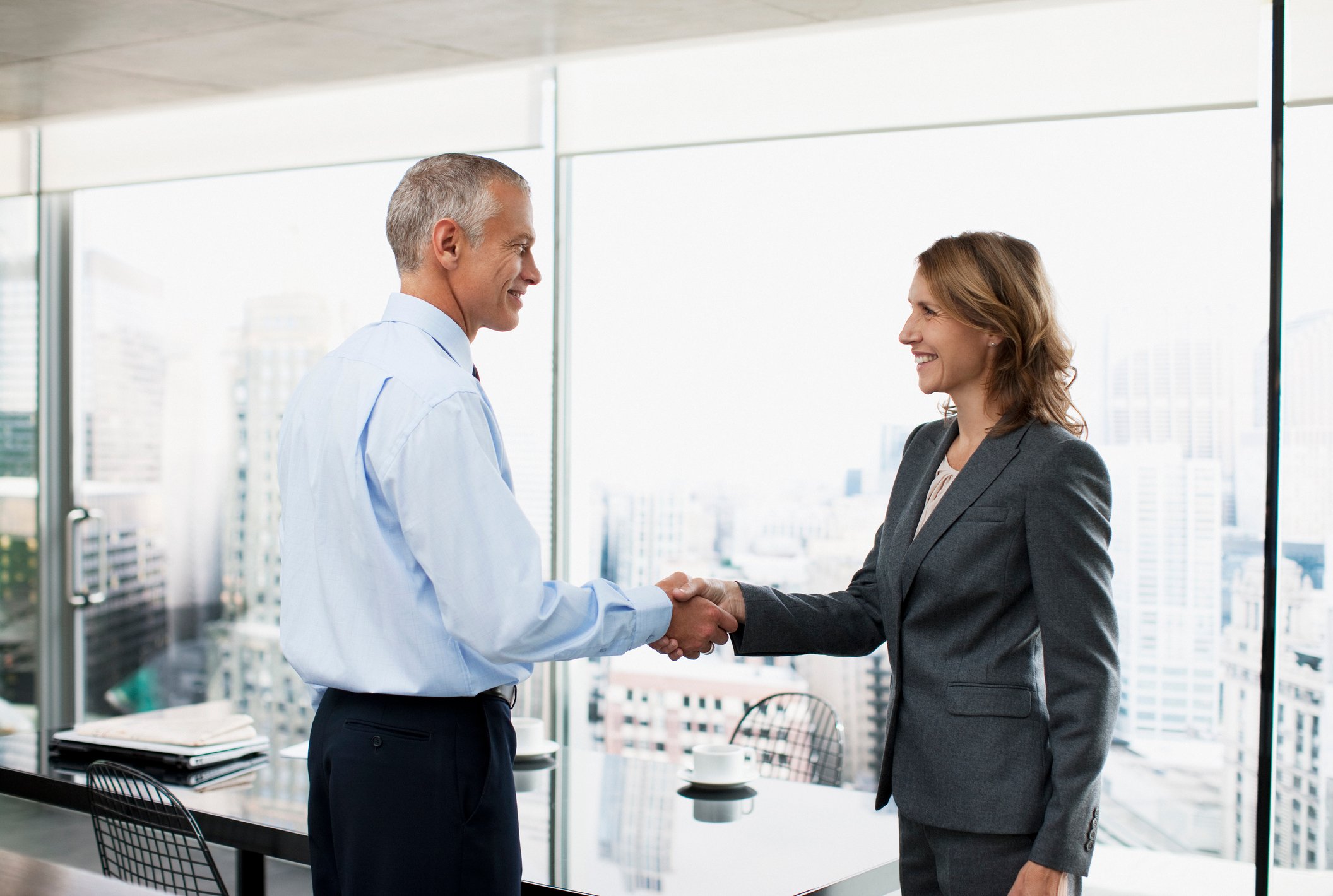 Professional older man shaking hands with a woman in a business suit