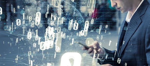 A person looking at a smartphone, overlaid with floating ones and zeroes.