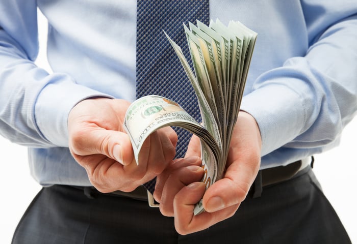 A man in business attire counting cash.