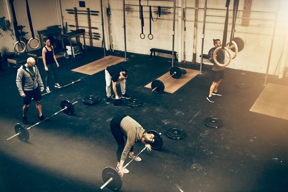 High angle of a group of fit people working out together during a weightlifting class at a gym.