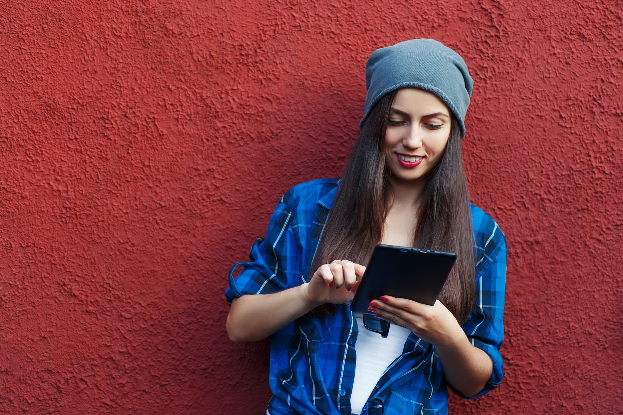 Young female adult wearing slouchy hat using a tablet