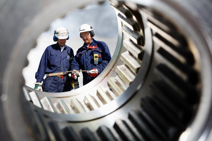 Two workers seen through a metal casing.