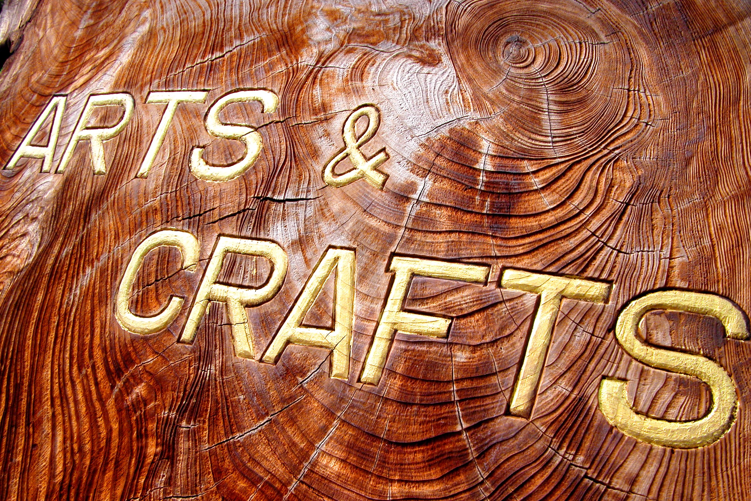 The words Arts & Crafts written in gold letters on a roughly hewn slab of dark wood.