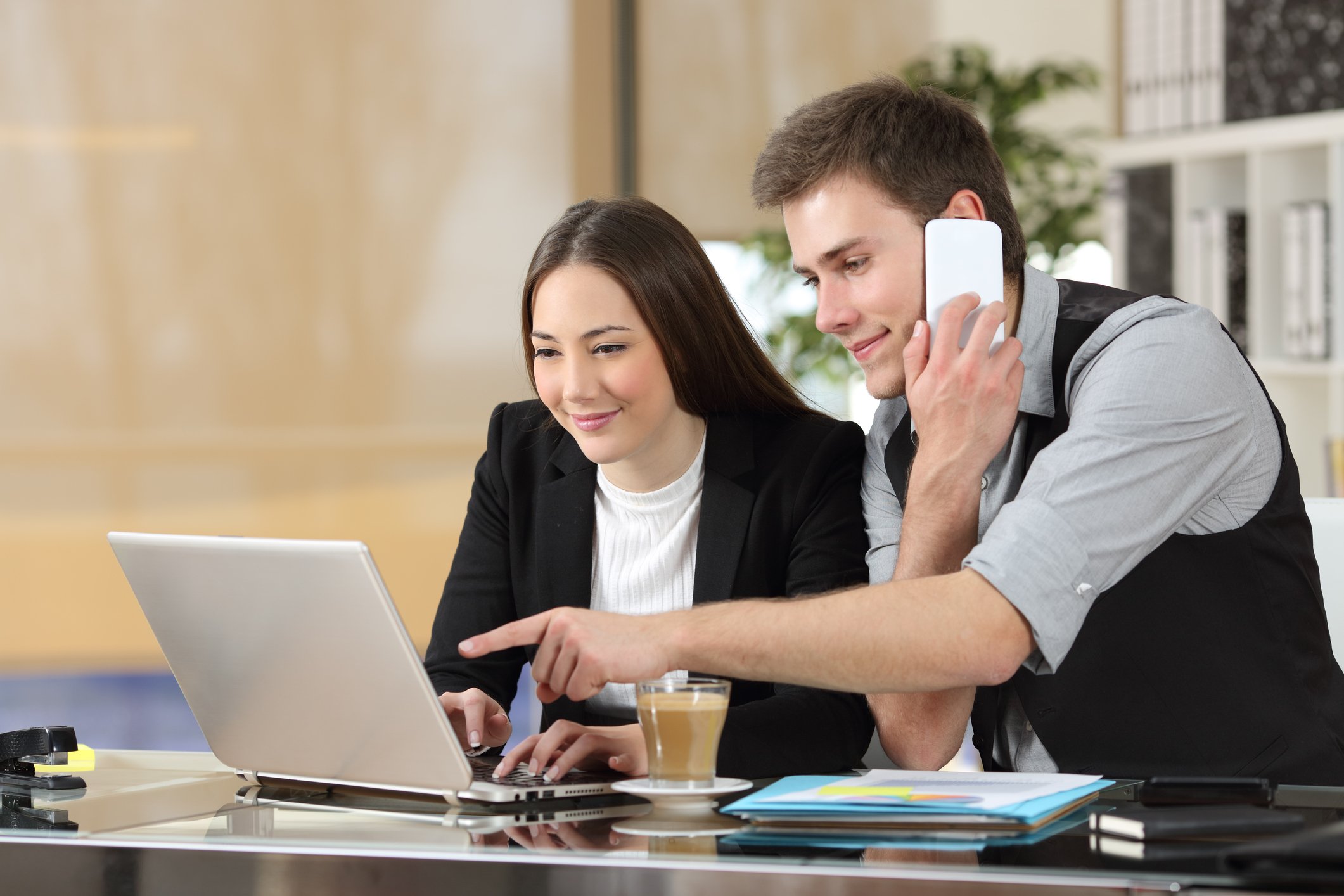 Two young businesspeople consulting over a laptop.