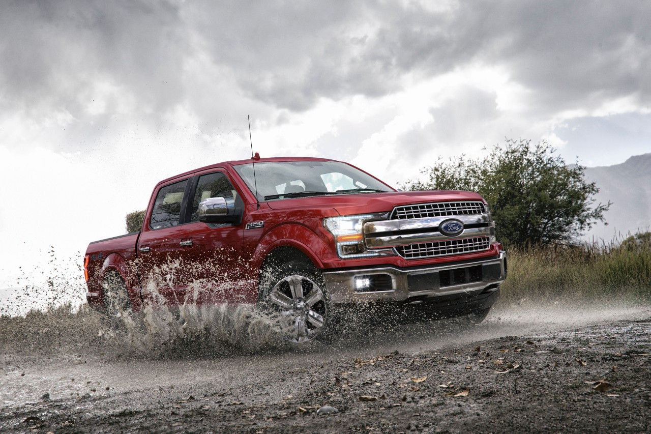 Ford F-150 Pickup driving on a muddy, wet, dirt road. 