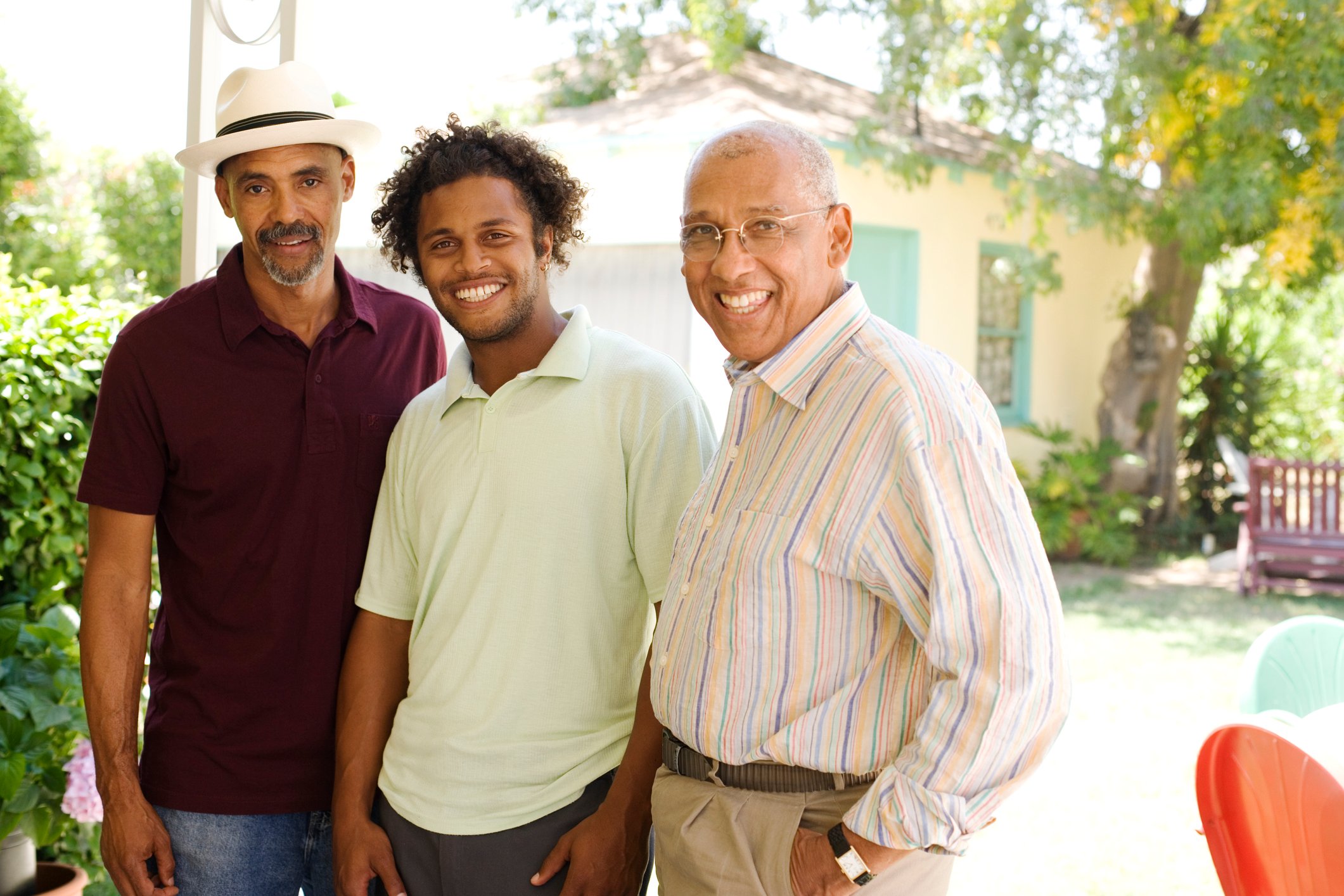 Three men standing next to each other and smiling in front of a house.