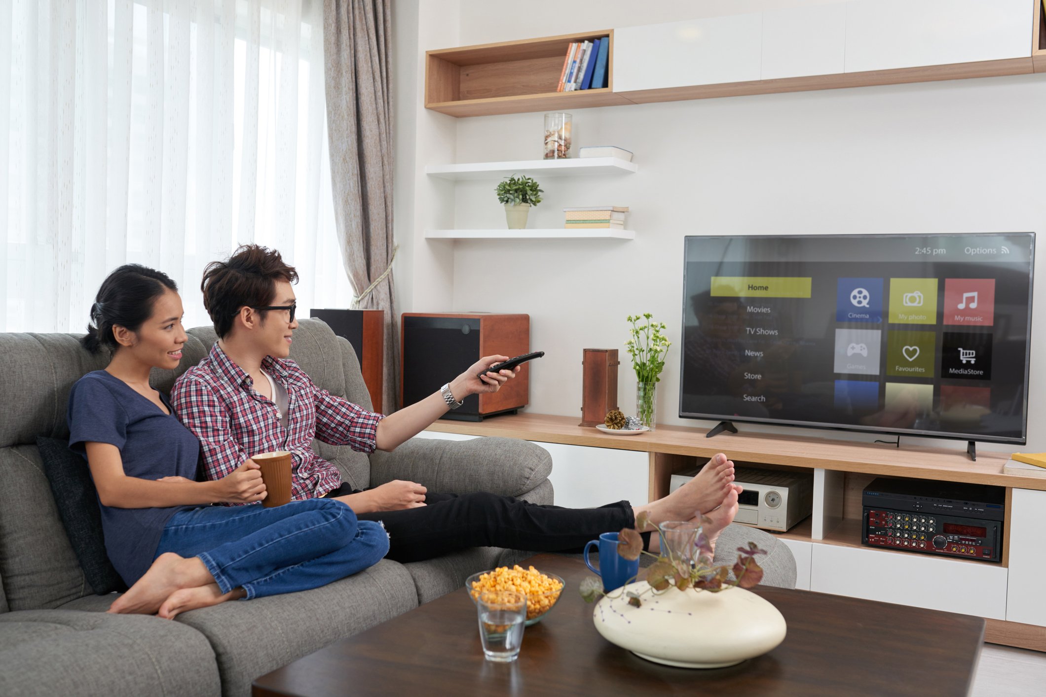 A couple sitting on a couch choosing an app to watch on a smart tv.